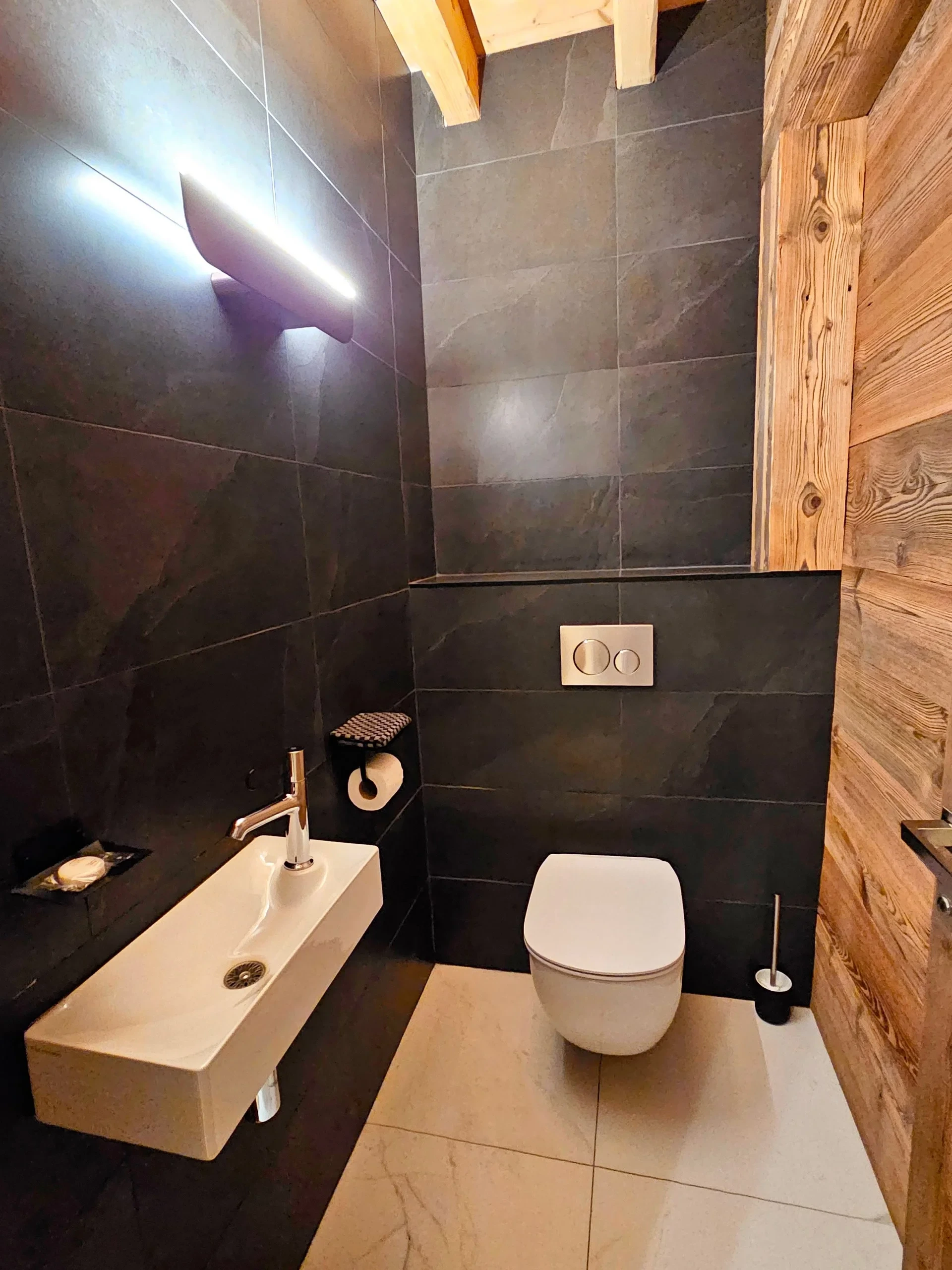 Toilettes modernes aux murs sombres et bois