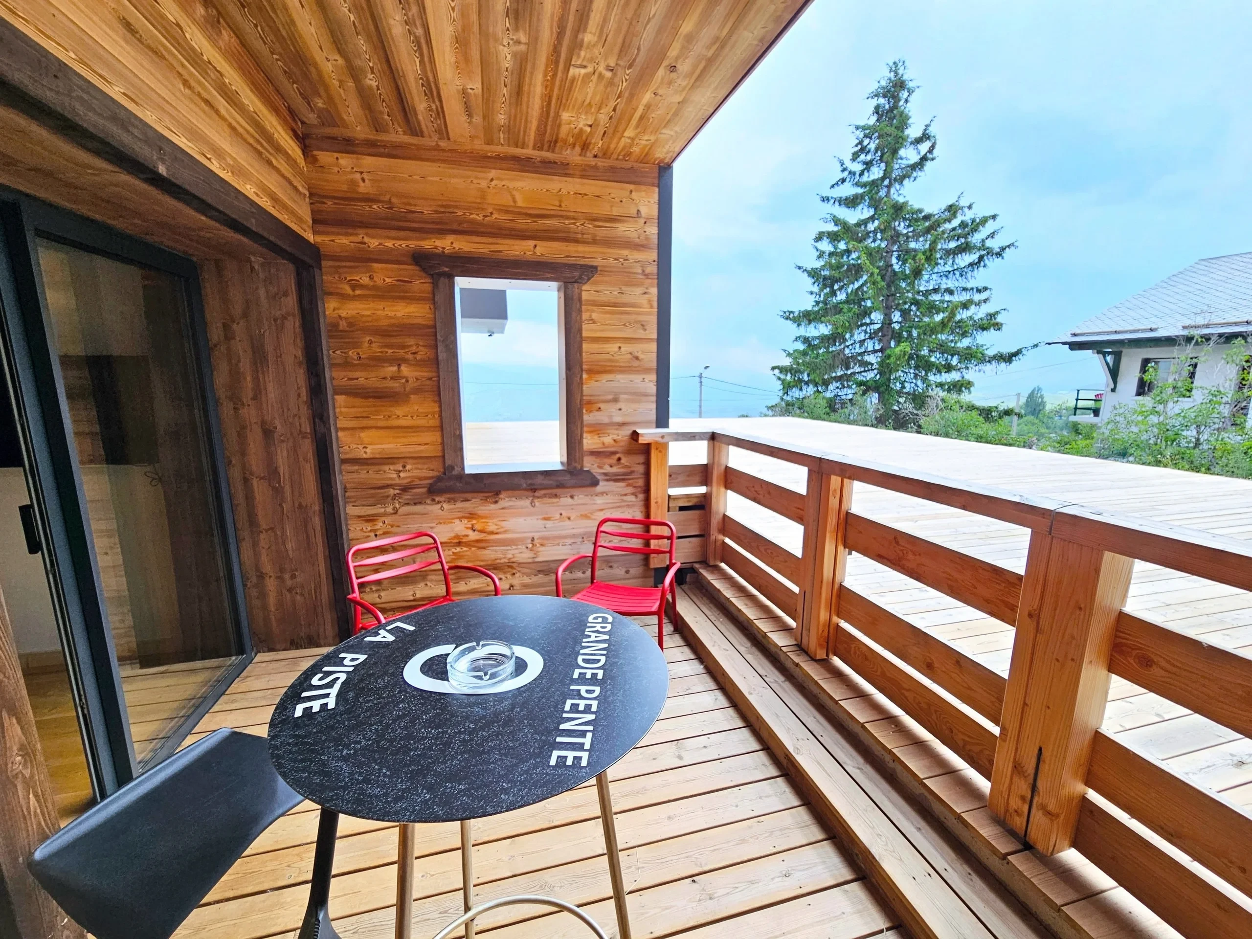 Balcon en bois avec table et chaises rouges