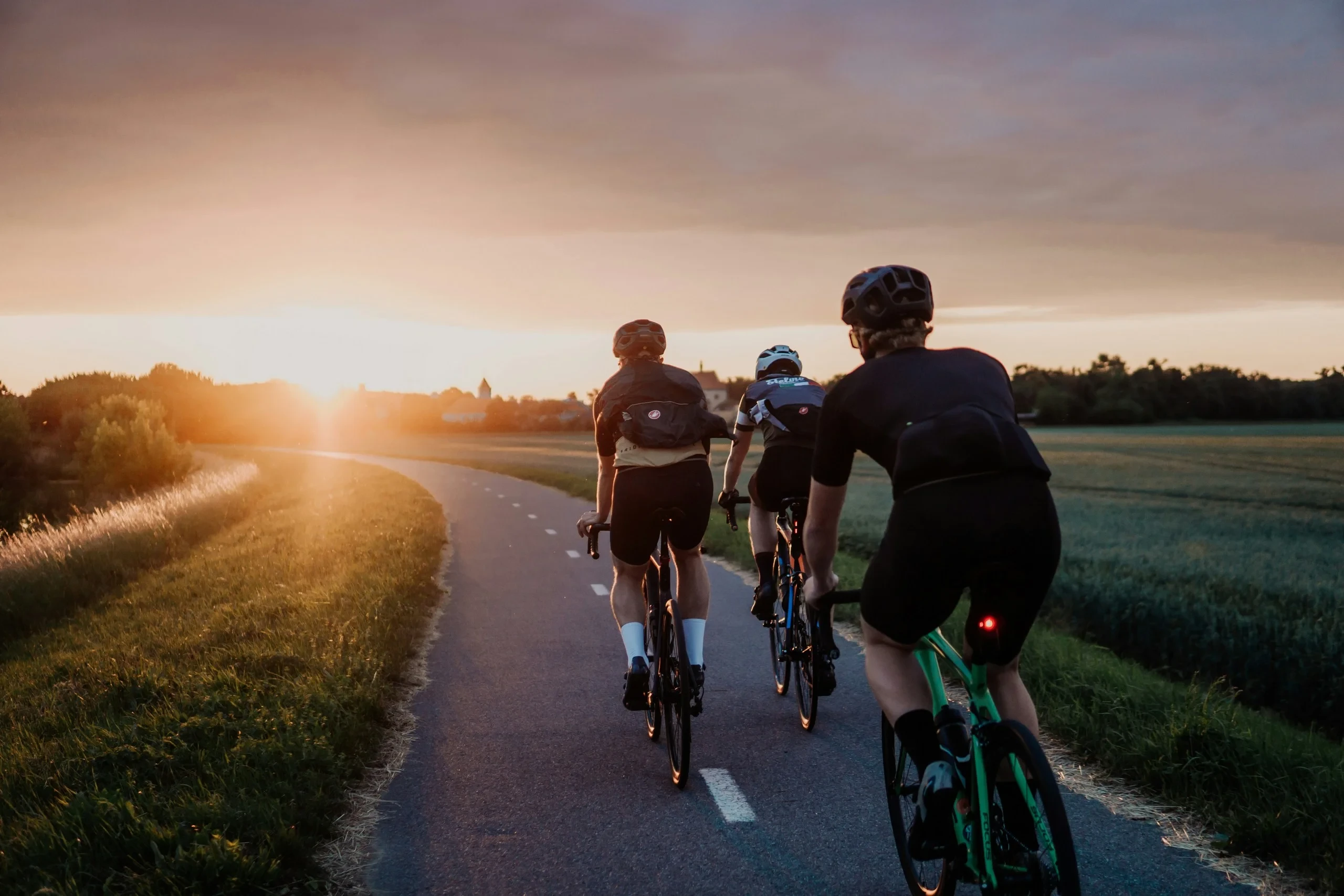 Trois cyclistes roulant au coucher du soleil