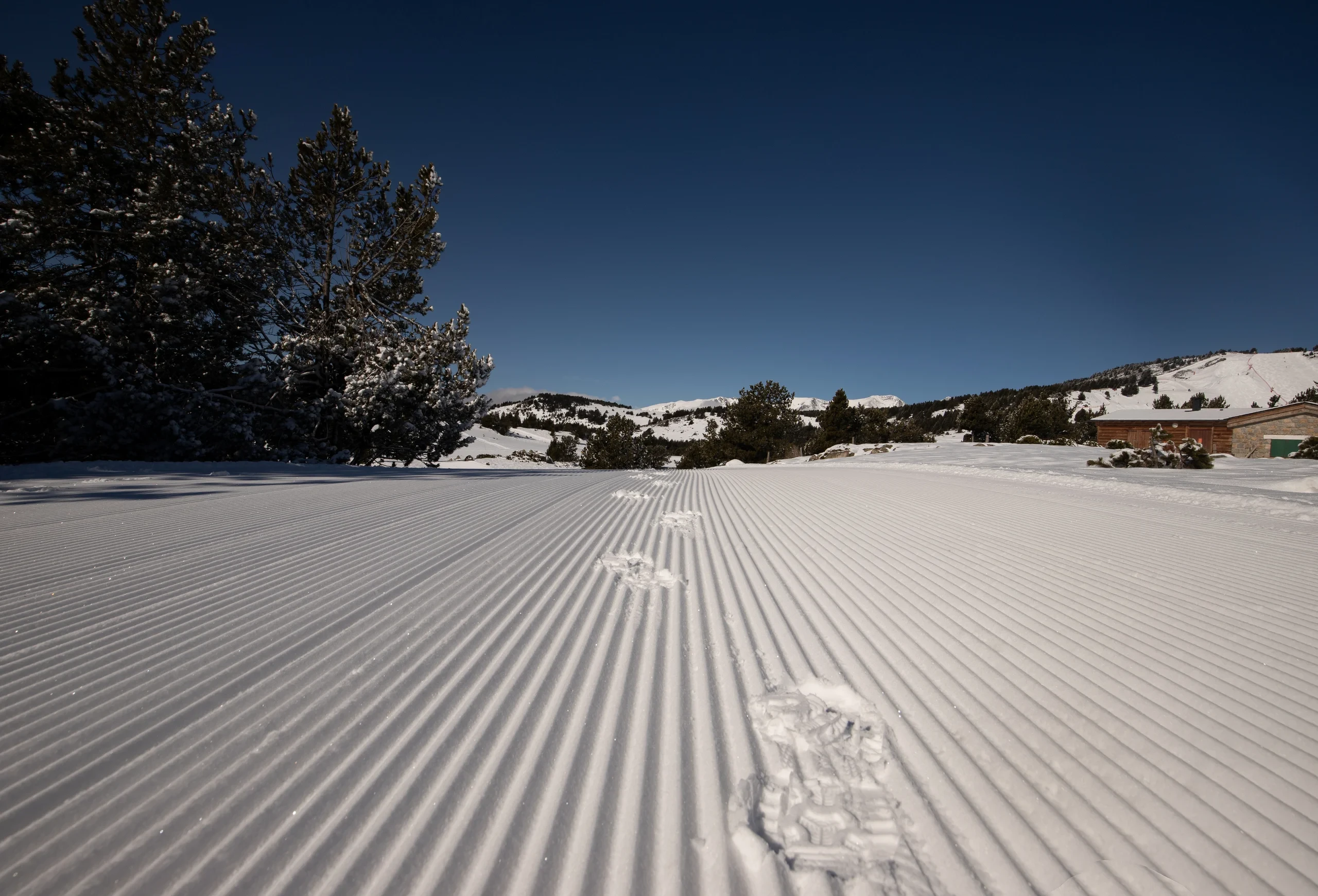 Traces dans neige damée en montagne ensoleillée