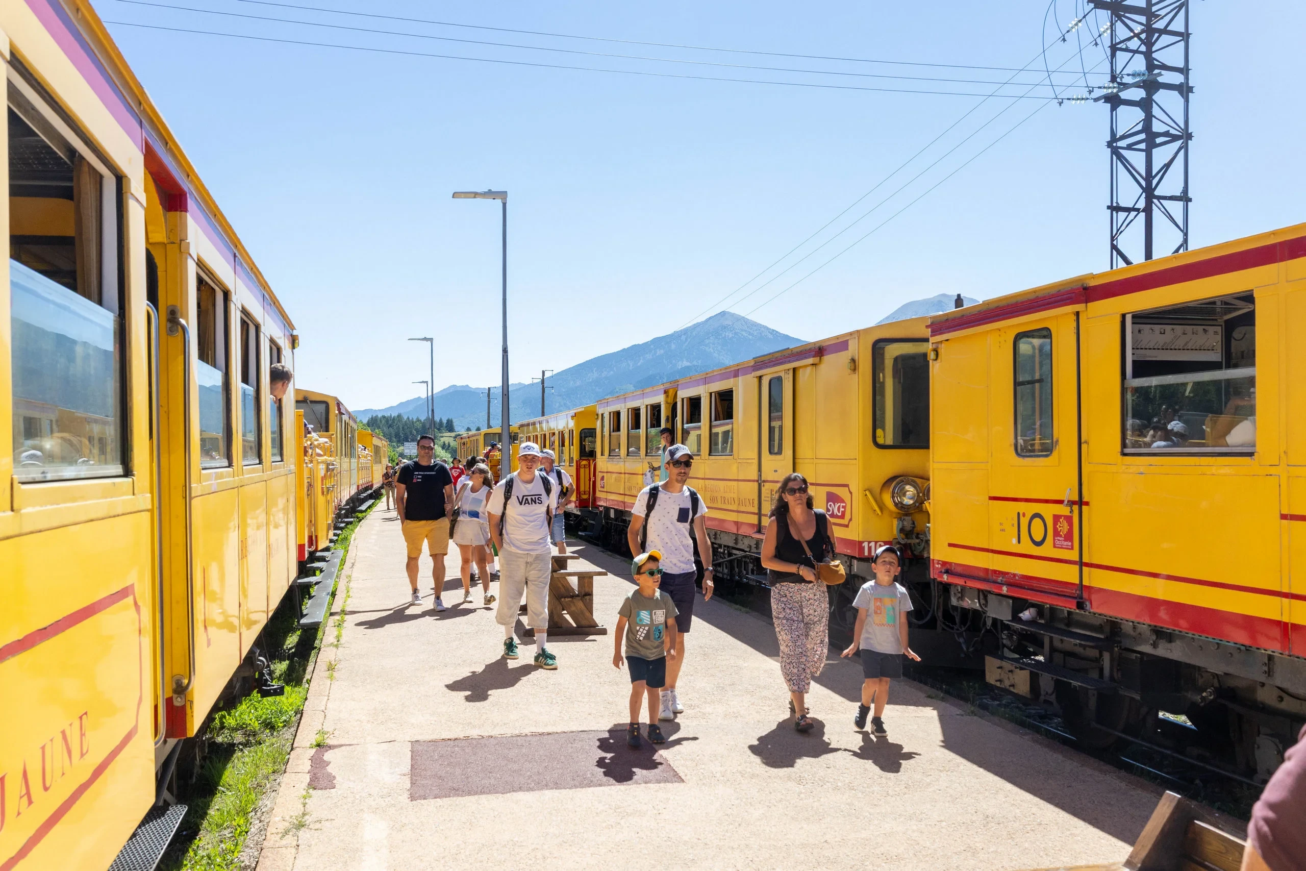 Voyageurs entre trains jaunes en gare de montagne
